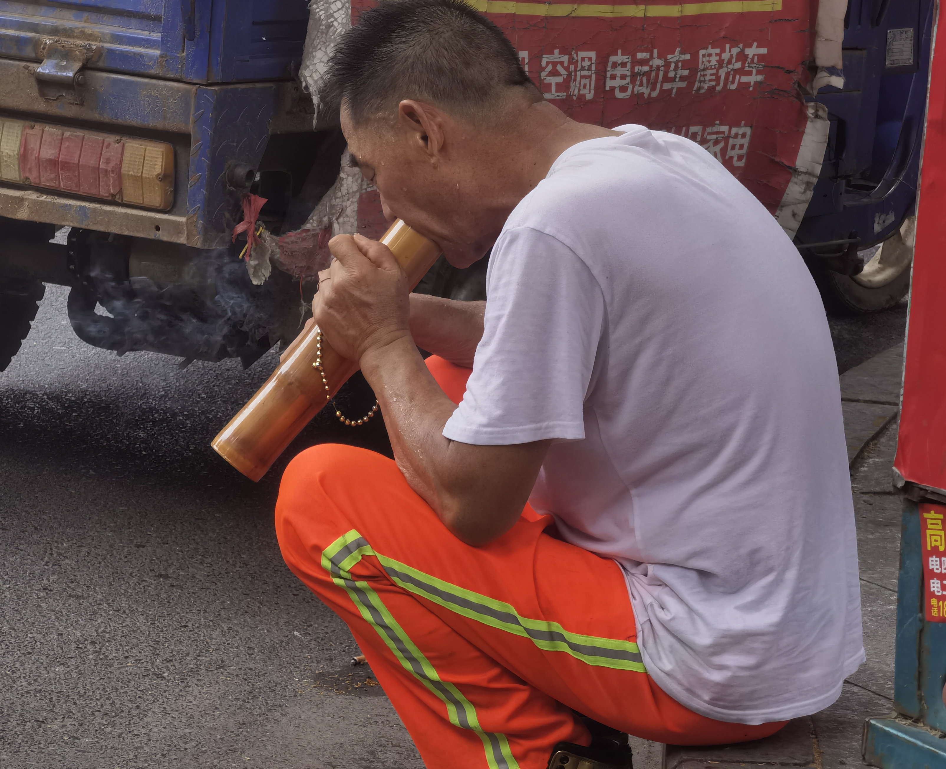 路旁见一位环卫工人,正手捧竹筒怡然自得地抽烟,抽的是那种细细的,一