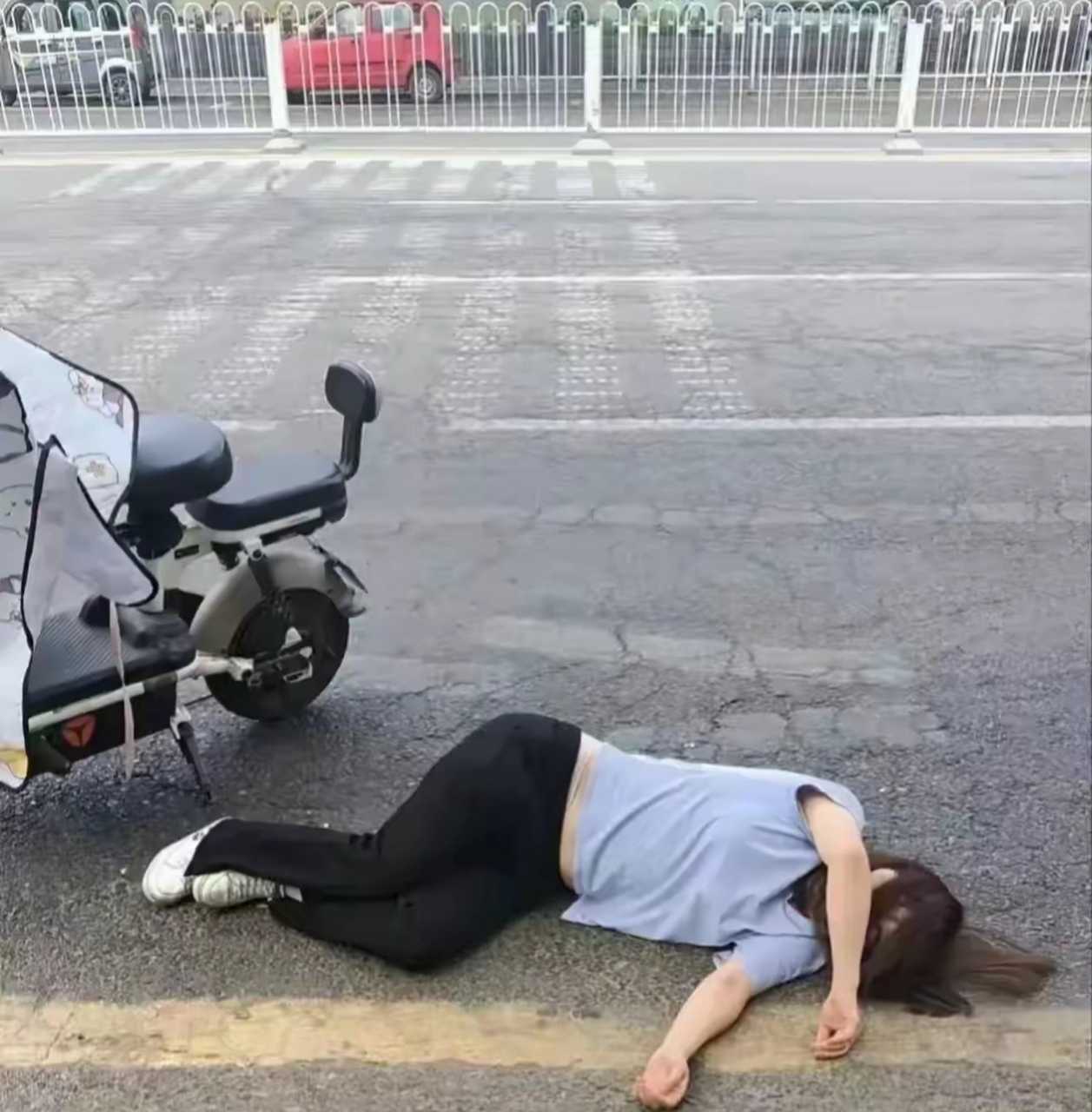 一位年轻的小姑娘不慎从电动车上摔落,她躺在地上,痛苦地挣扎,久久才