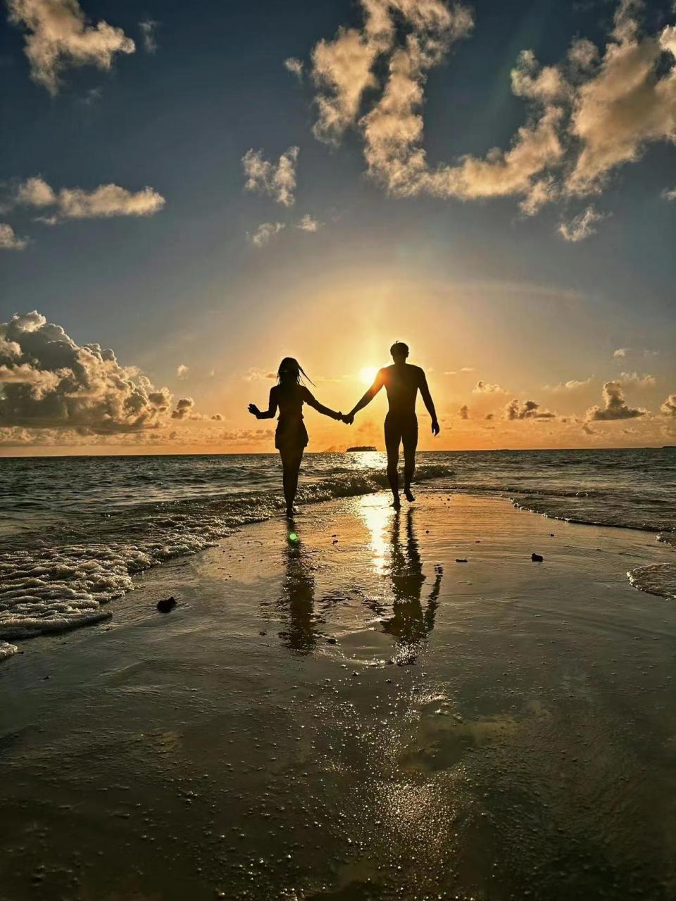 夕阳西下,一对情侣在海边散步,他们大声叫着:"日落海边,许个心愿".