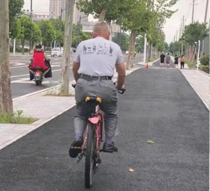 在回家的路上,看见一位身着白背心的大爷,正悠然自得地骑着自行车
