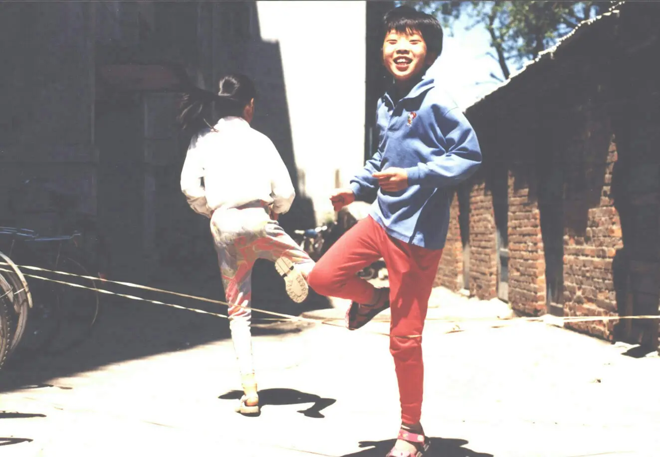 是跳皮筋游戏,这张照片就真实记录了当时的场景,也是一代人的青春记忆