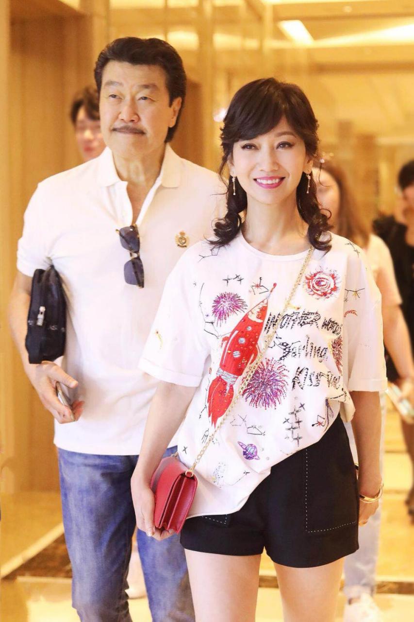 赵雅芝穿黑短裤配印花t恤,脚踩高跟鞋走机场