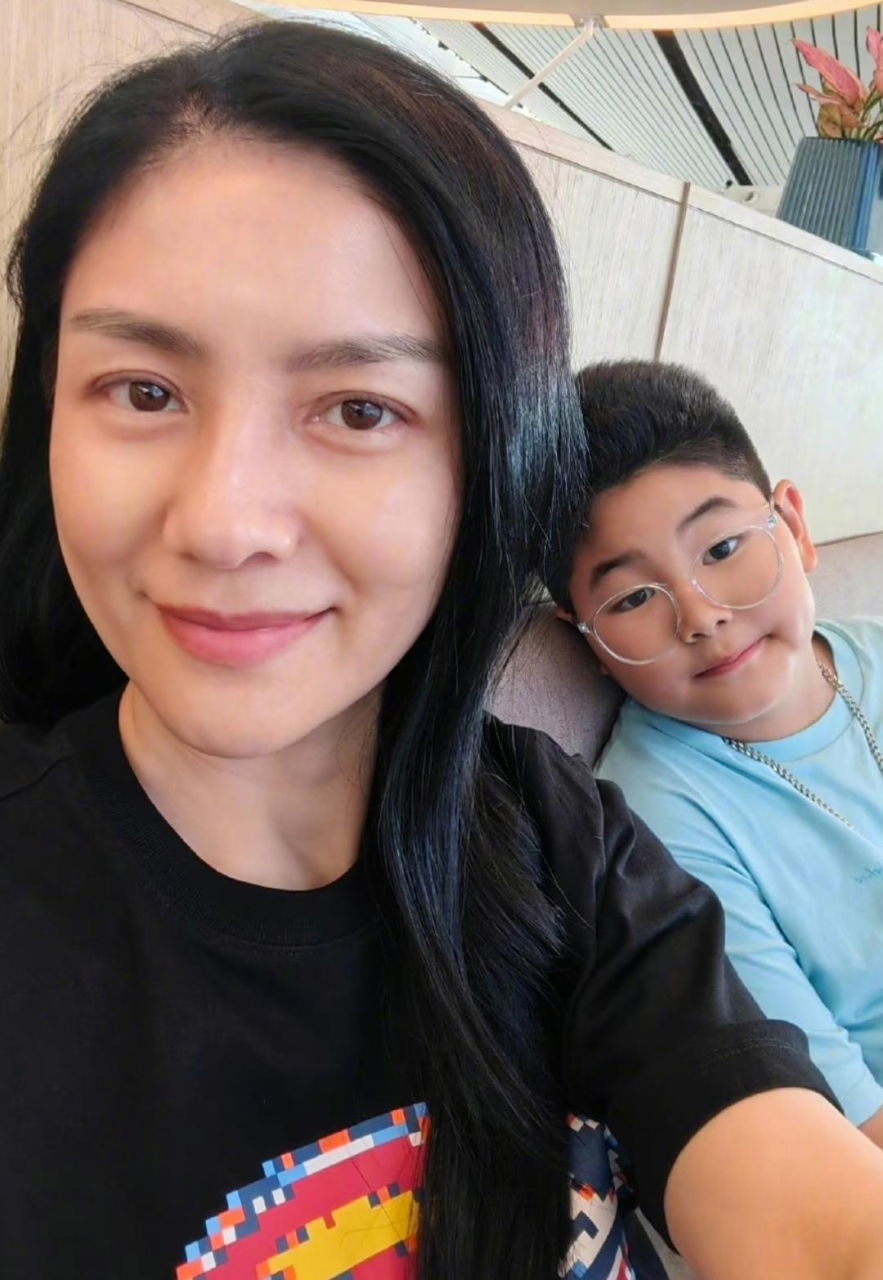 二儿子小鱼儿戴上眼镜了,坐在沙发上配合妈妈拍照,胖乎乎的脸型很喜庆