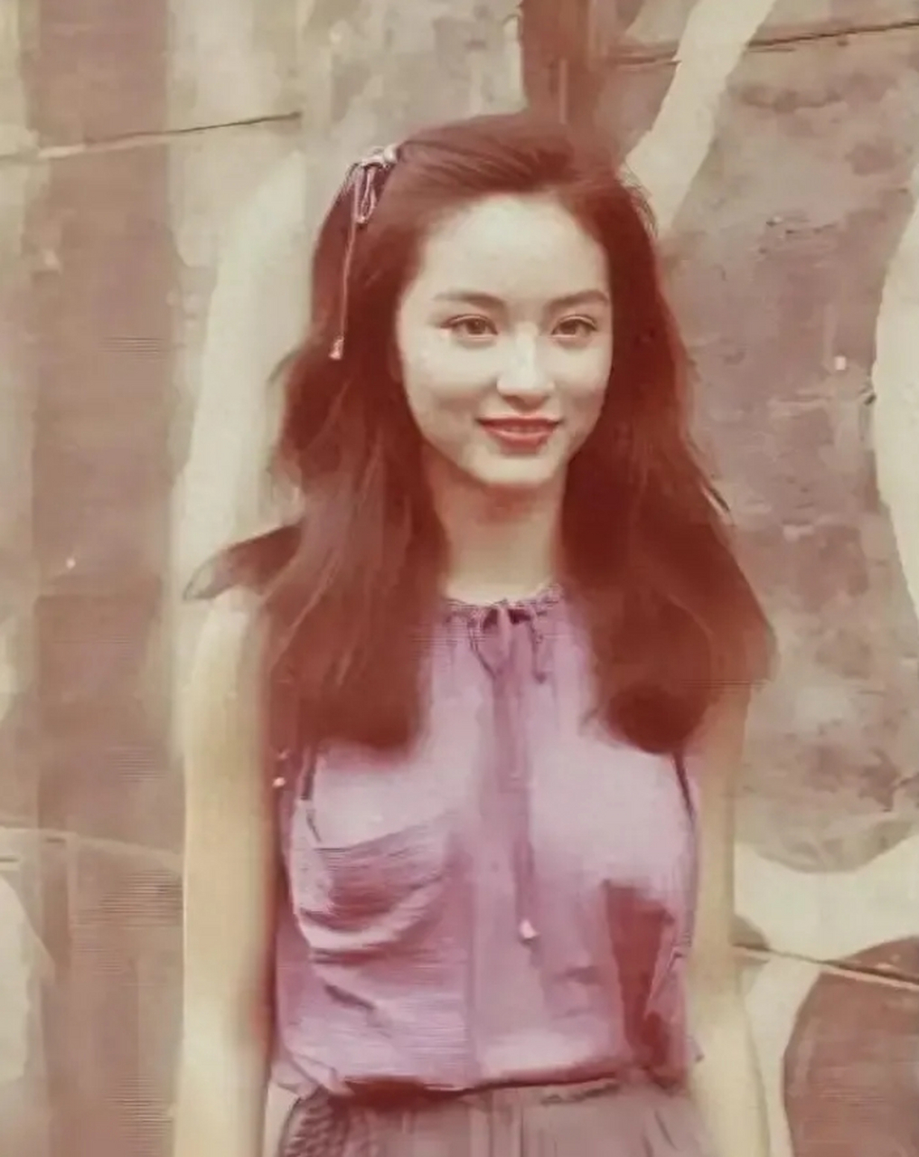 林青霞年轻时的甜美留影,照片中,她身着一件紫色无袖丝质上衣,如同