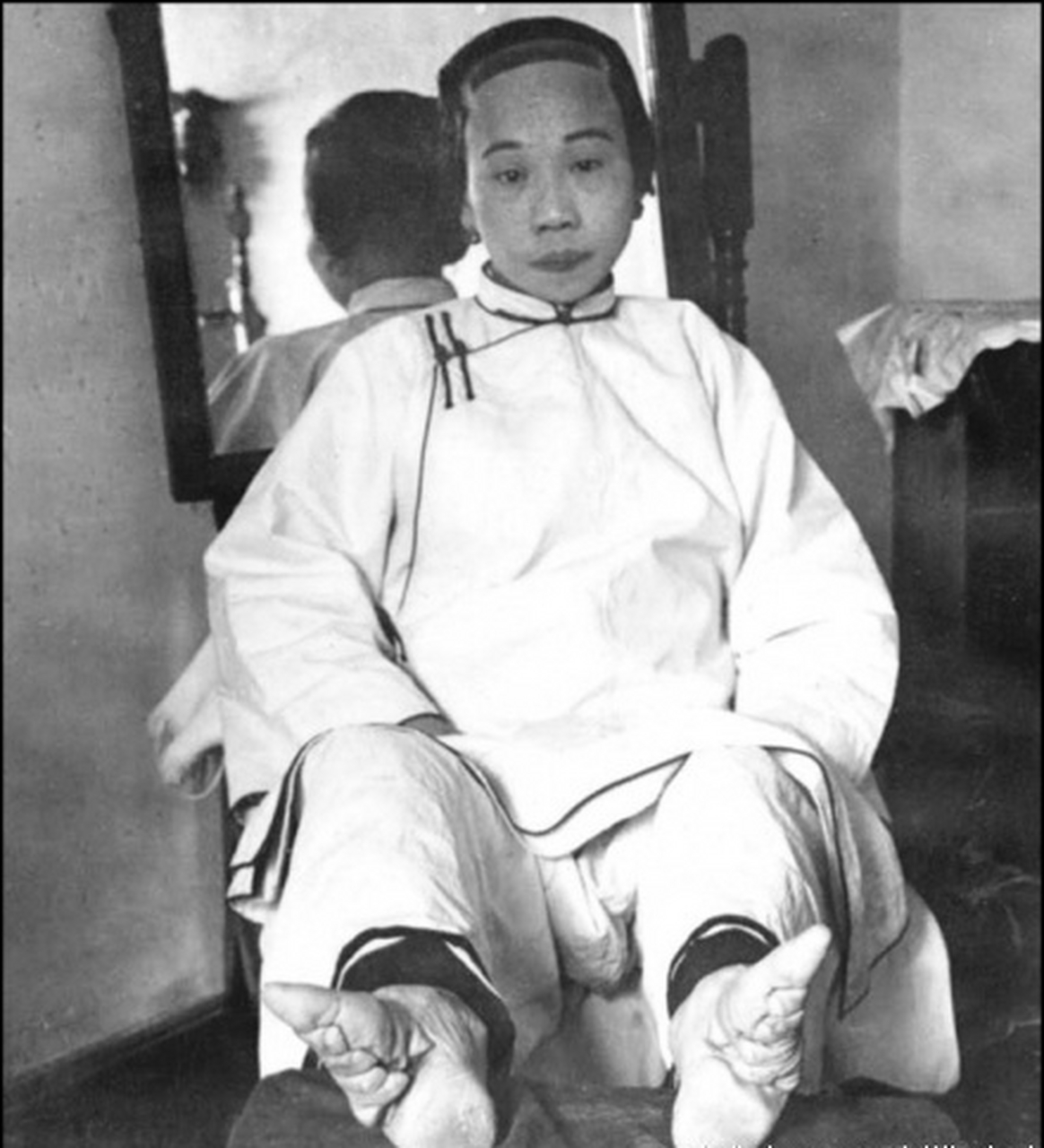 晚清时期,一位面容姣好的小脚女人在镜头前展示自己的"三寸金莲"