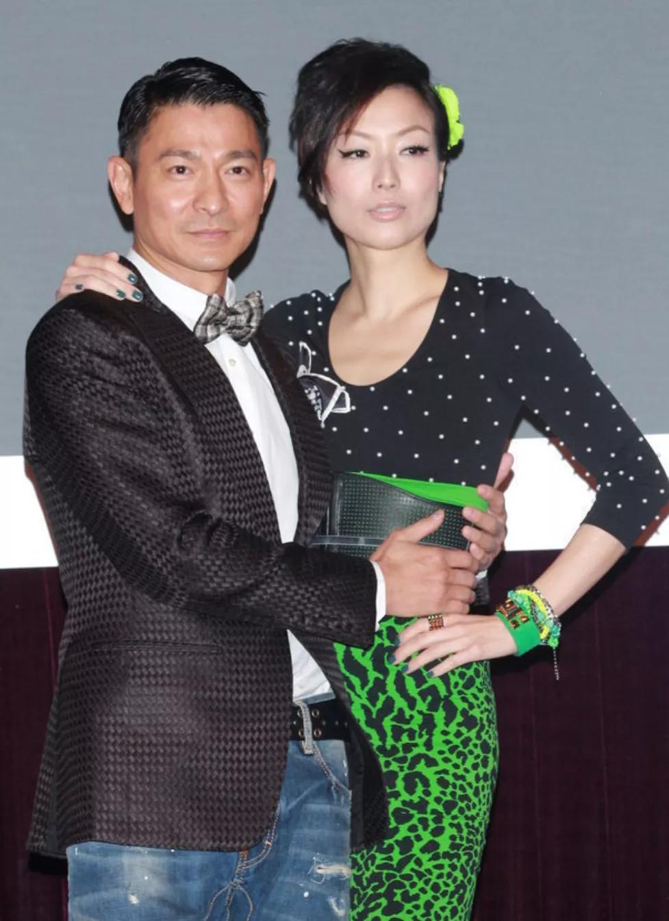 刘德华双手搂着这个女人的腰,这个女人也搂着刘德华的肩膀,还叉着腰