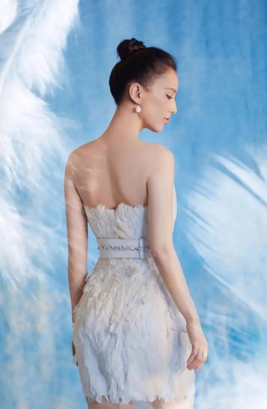 干练的丸子头,洁白的羽毛抹胸长裙让黄圣依看起来更加纯情,这穿搭真是