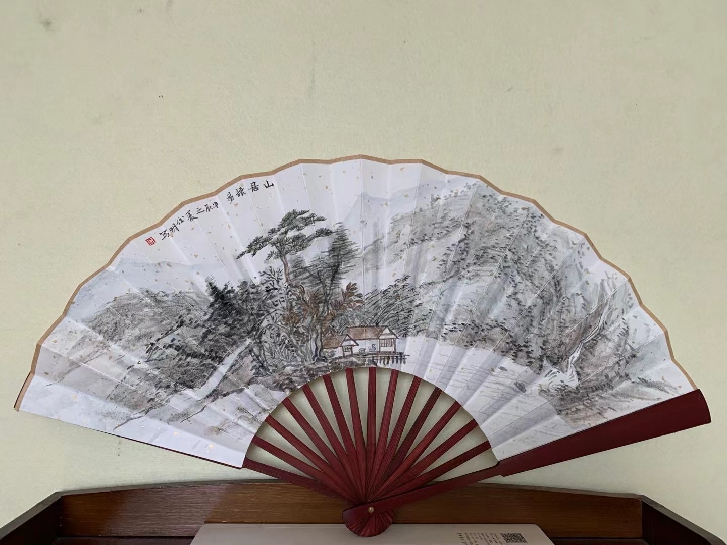 扇子的骨架部分是红色的,与扇面的山水画形成