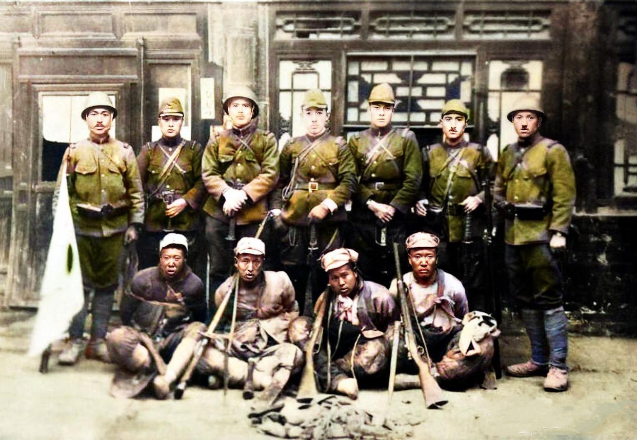 1937年,太原沦陷后,日军与四名被俘的国军士兵合影