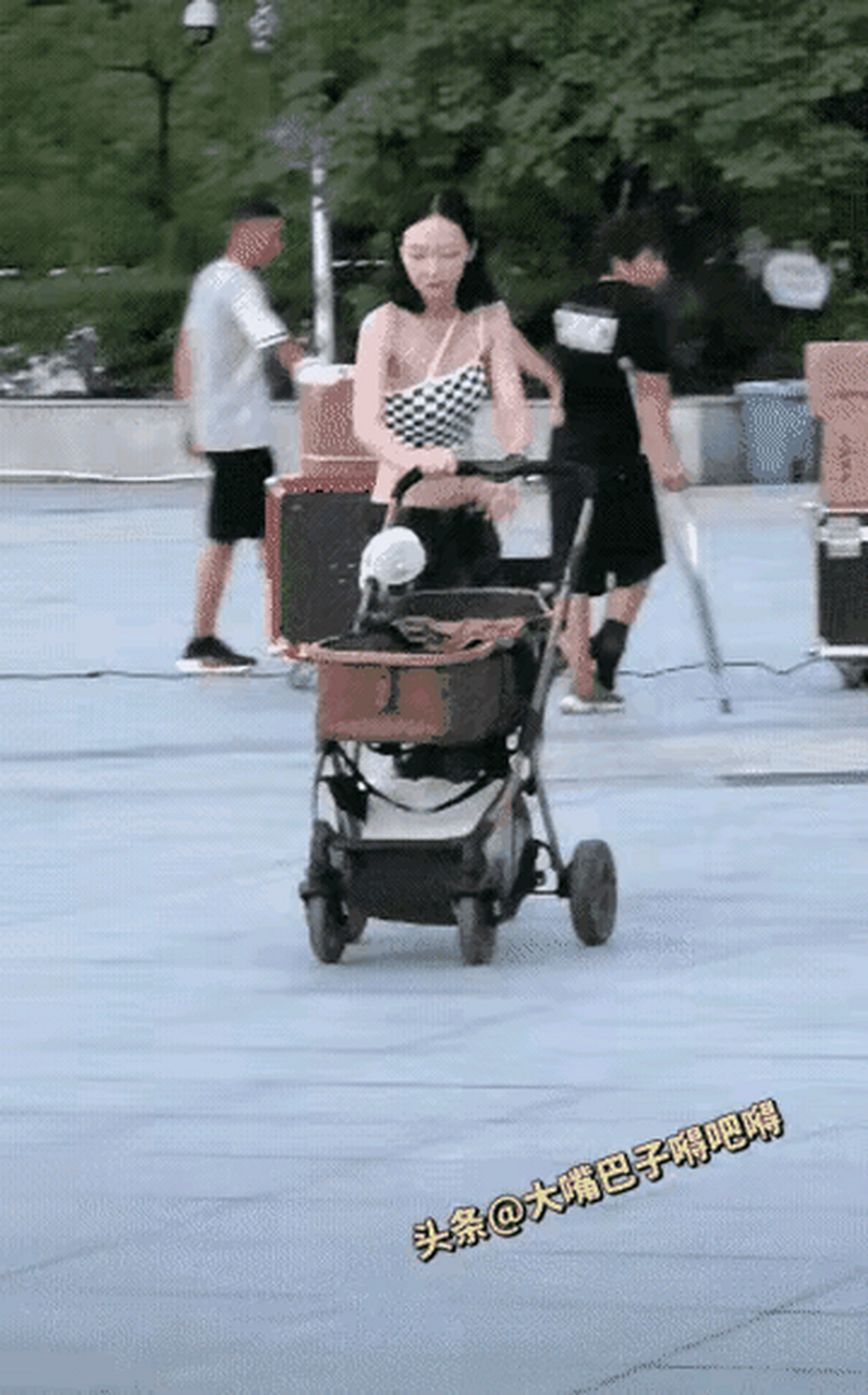 一个漂亮的女人,推着一辆婴儿车,在公园游玩,她看着孩子睡着了,女人把