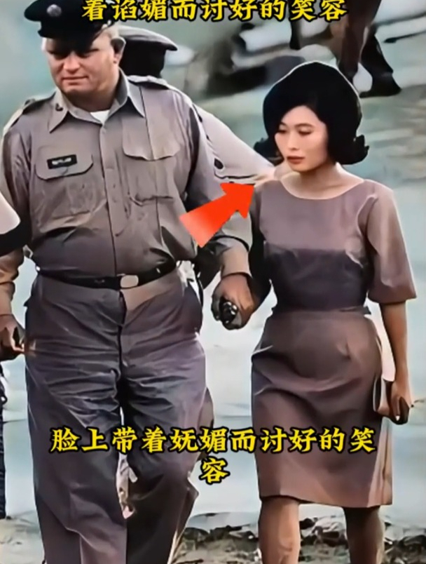 一名美国军官手牵着一个日本女人,女人脸上带着谄媚而讨好的笑容