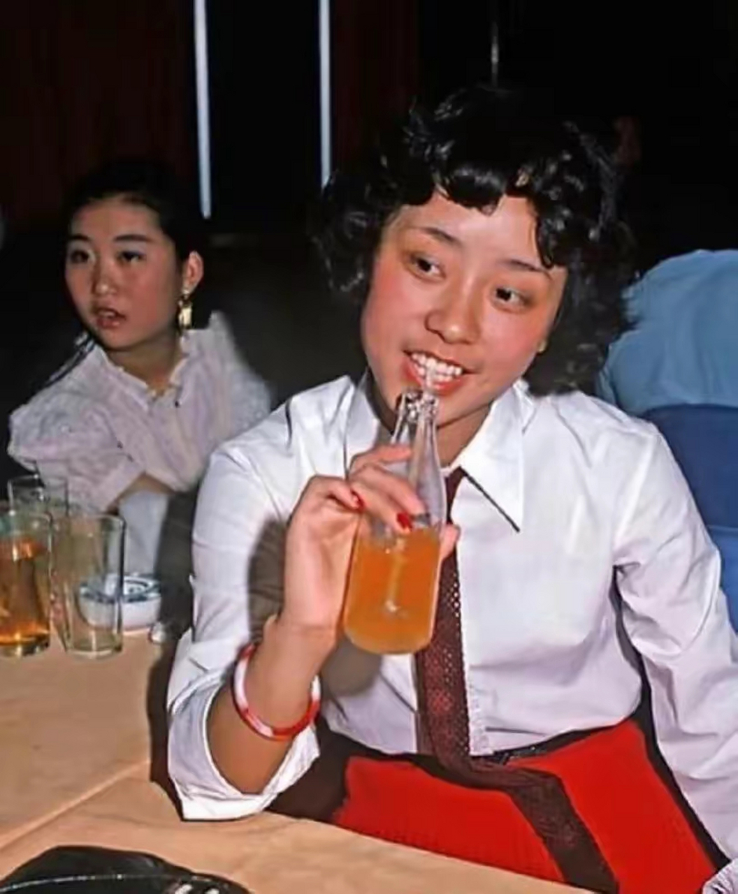 上世纪80年代上海的老照片,几个穿着时尚的少女撑着油纸伞在公园里面