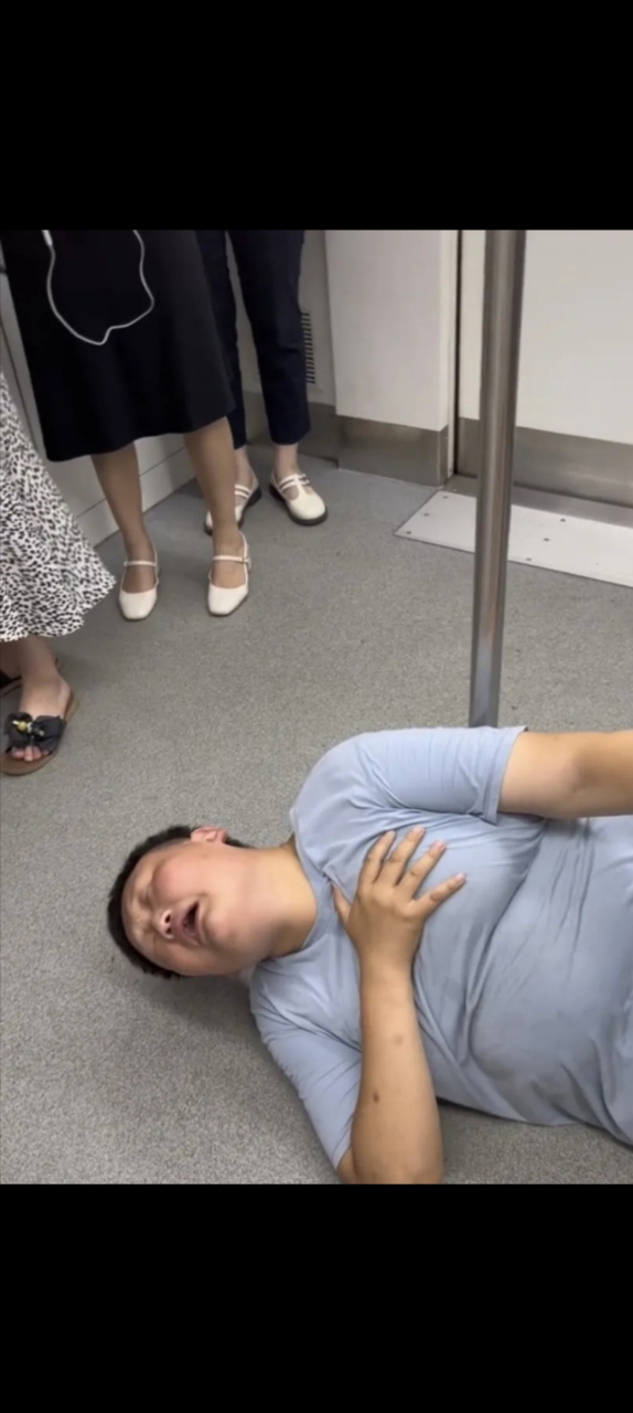 重庆,地铁车厢中,一名男孩长相的人突然倒地不起,用手捂着自己的胸口
