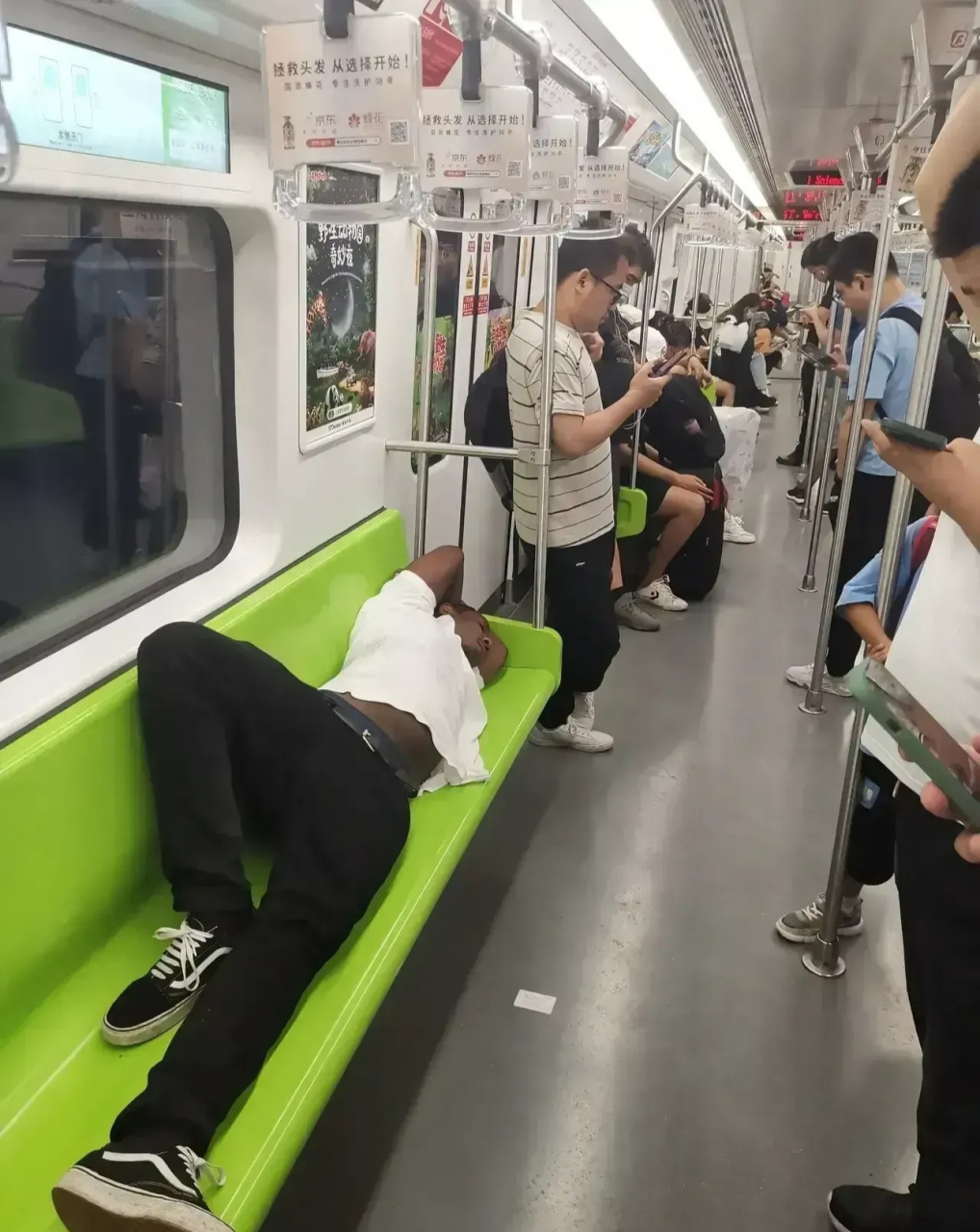 今天在上海地铁2号线上,一位黑人外国人霸占了一整排座位,让人们感到