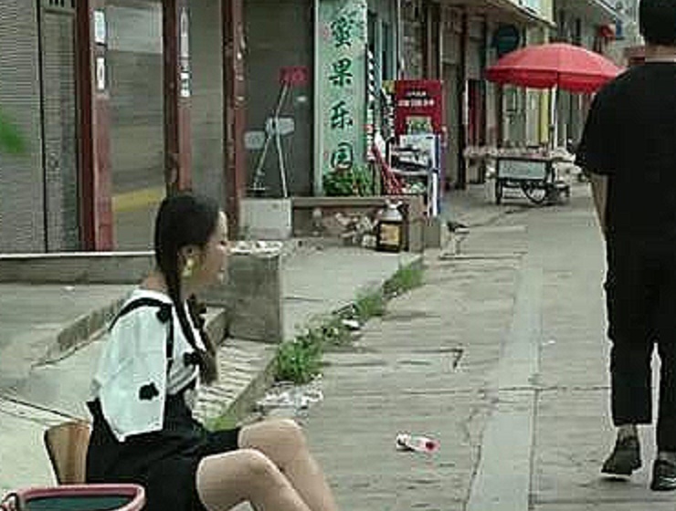 广西南宁:一失去双手的残疾女孩正在马路边上卖石榴