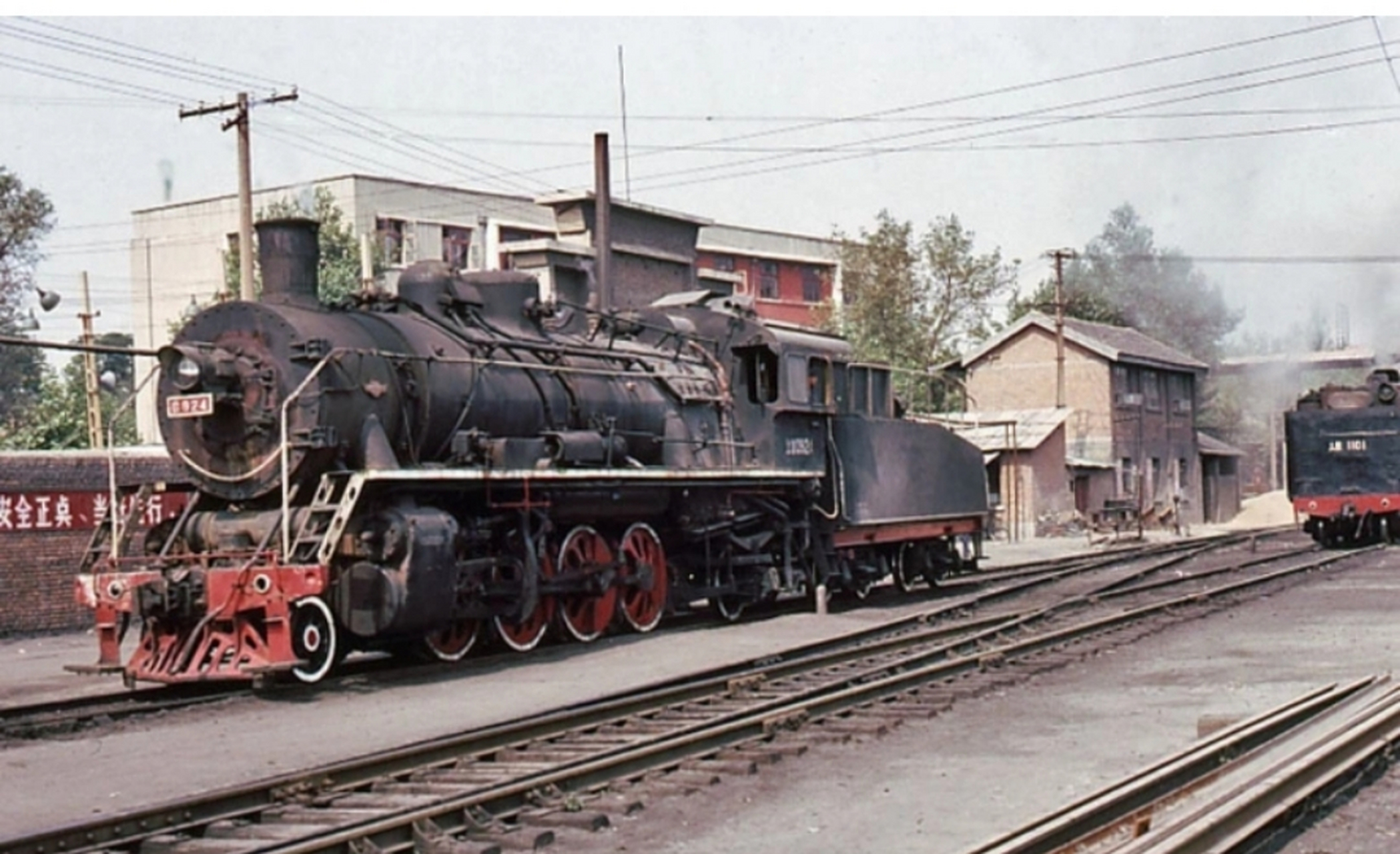 八十年代古城西安老照片,一个站台,停着一台火车头,还有一辆火车正在