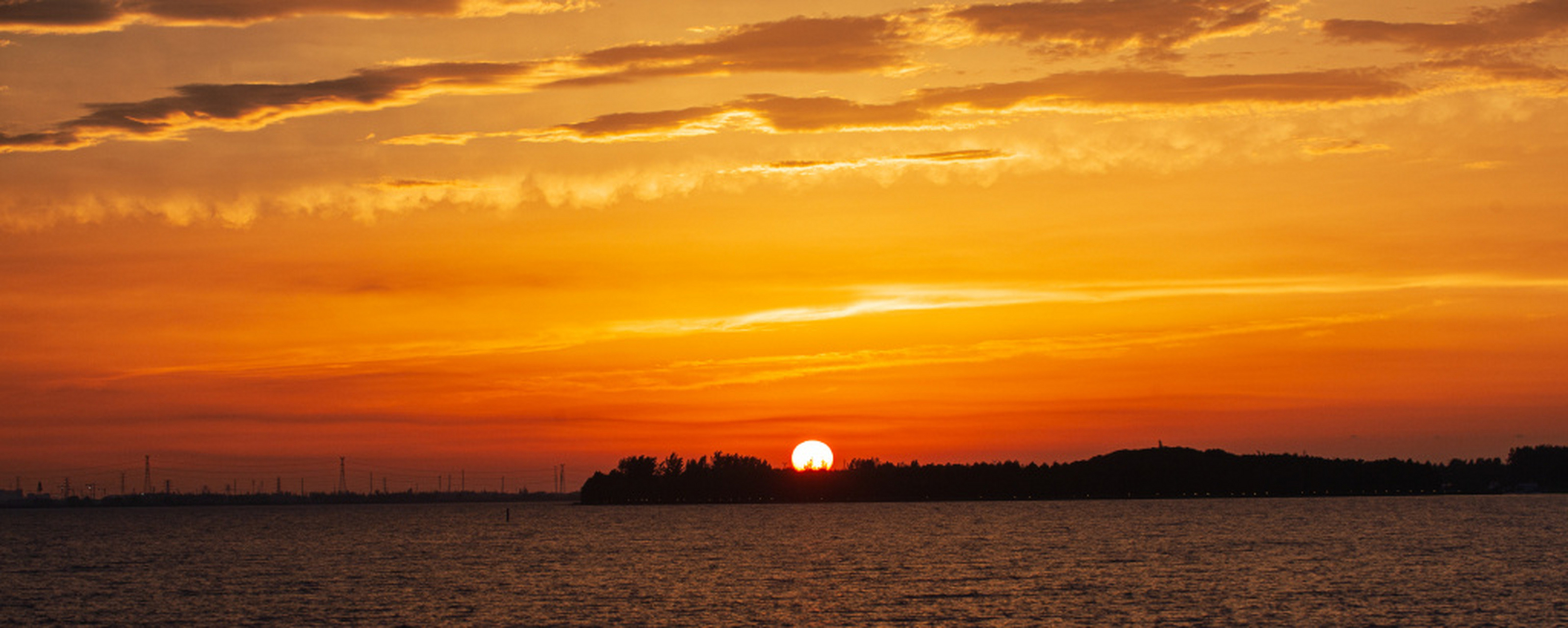 日暮时分,晚霞映照苏州湾,远处的建筑屹立在落日之中,天边和水面被