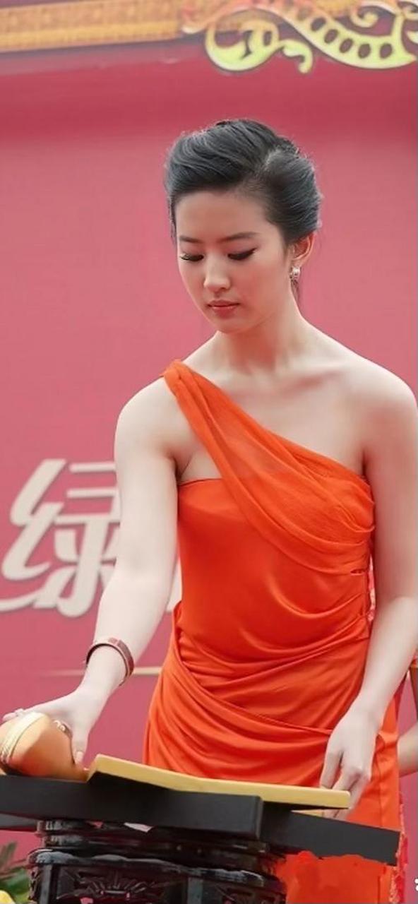 刘亦菲的这条橘红色的连衣裙采用了不对称的斜肩设计,展现出了她局侣