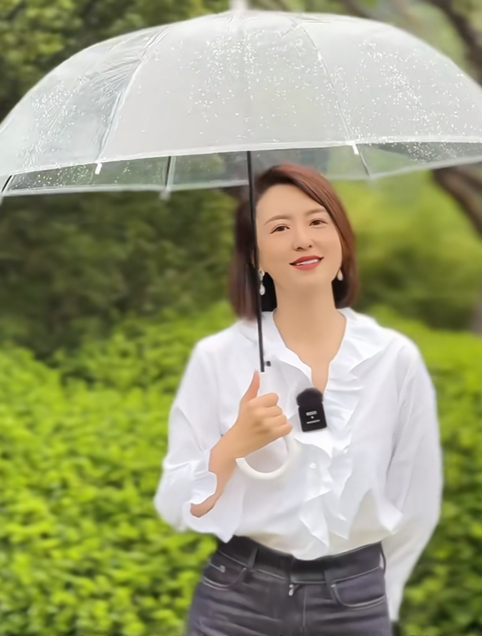张蕾拍外景短片,为了节目效果特别撑了一把透明雨伞,配合她的白衬衫和