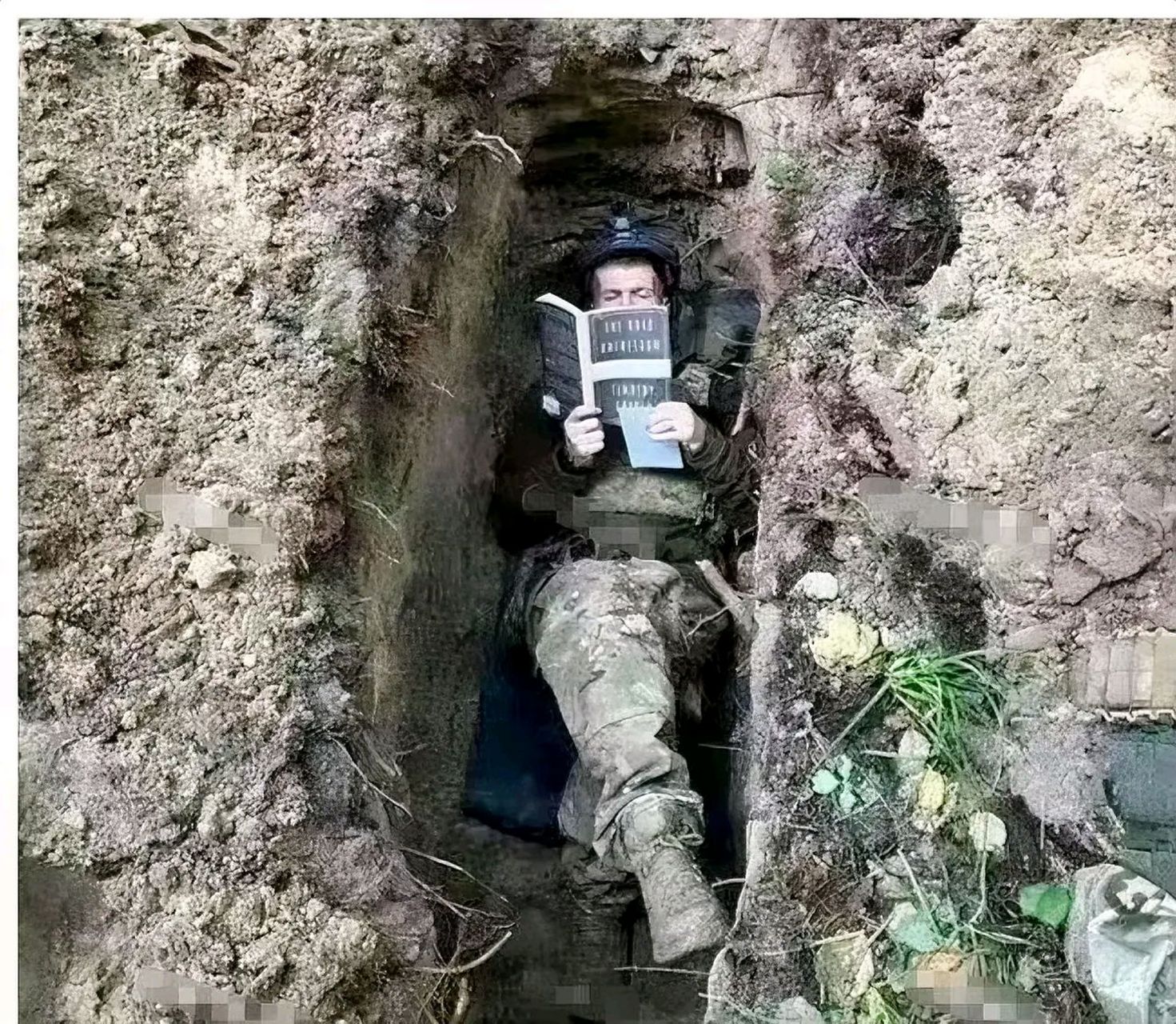 这是无人机拍到的画面,一年轻的乌克兰士兵正躺在战壕里看书.