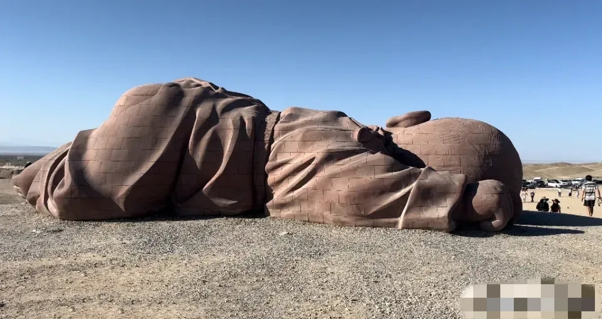 甘肃酒泉市瓜州县的戈壁滩上,"大地之子"的身上,一个女游客竟然爬上其