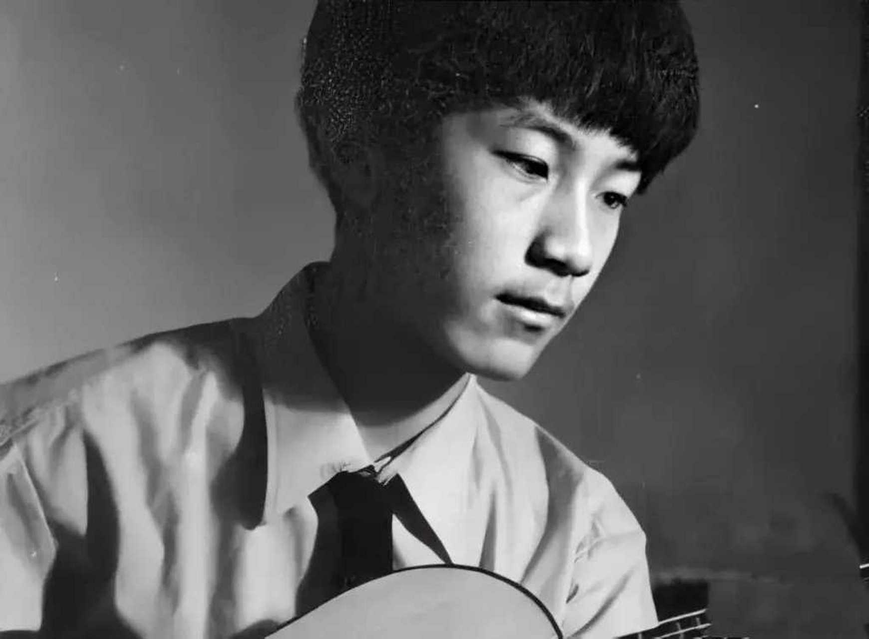 上世纪70年代,一个穿着皮夹克,弹着吉他少年的照片.