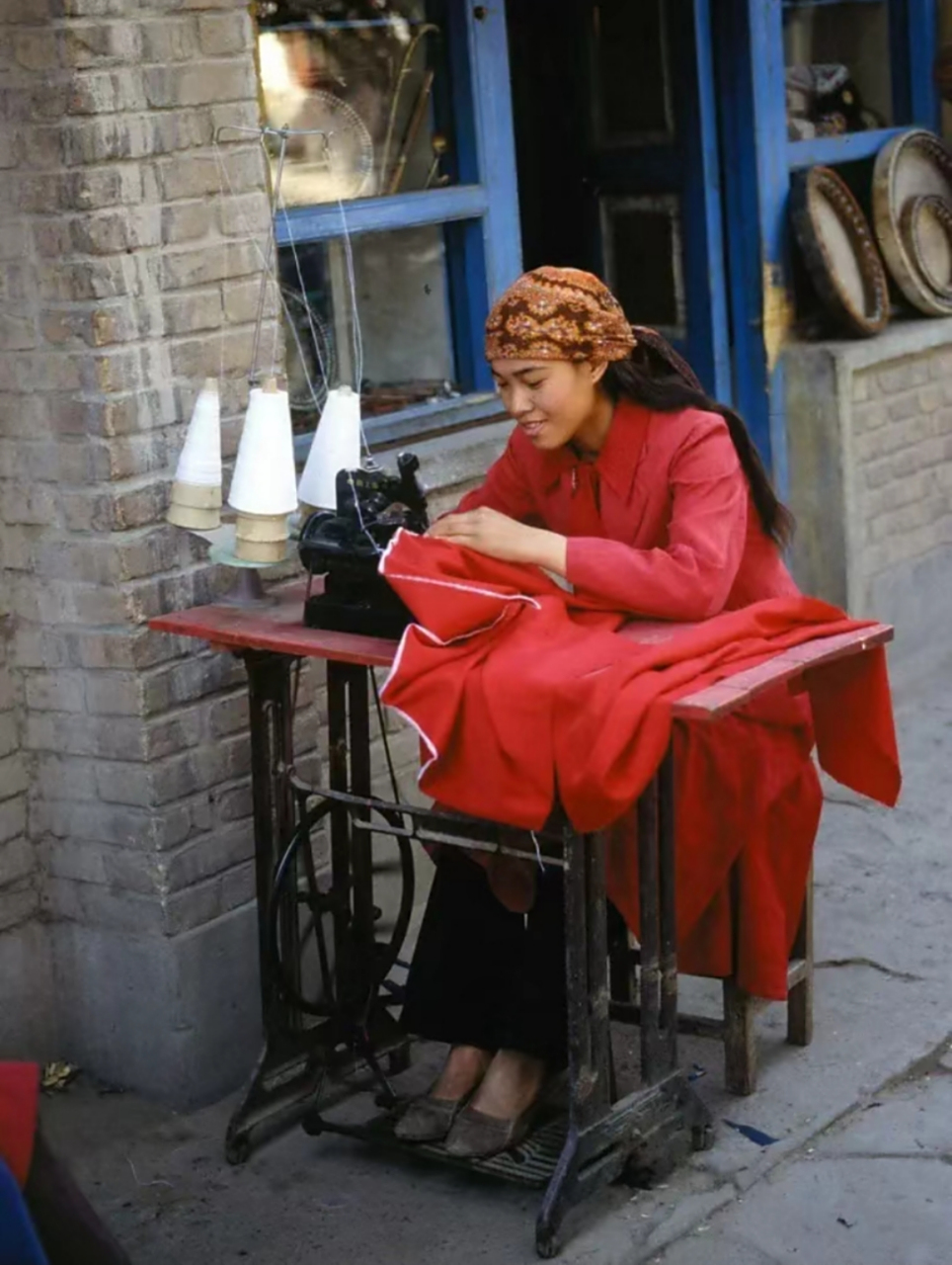 八十年代,新疆喀什老照片,一一位穿着红色衣服的少数民族女子,正在用