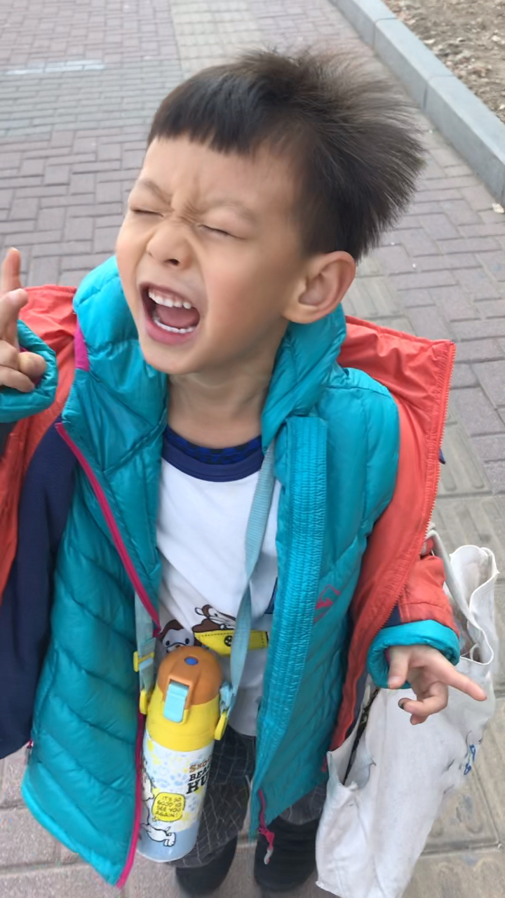 小男孩幼儿园放学路上自己背书包挂大水壶,还帮妈妈提好大个袋子,开心
