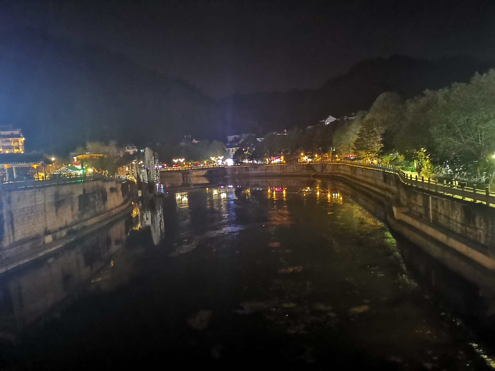 小巷位于河边,夜间马路两边的楼上灯都亮了,给人璀璨的感觉.