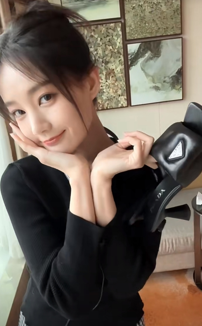 李一桐在窗户边美美自拍,手里拿着新的高跟鞋,黑色