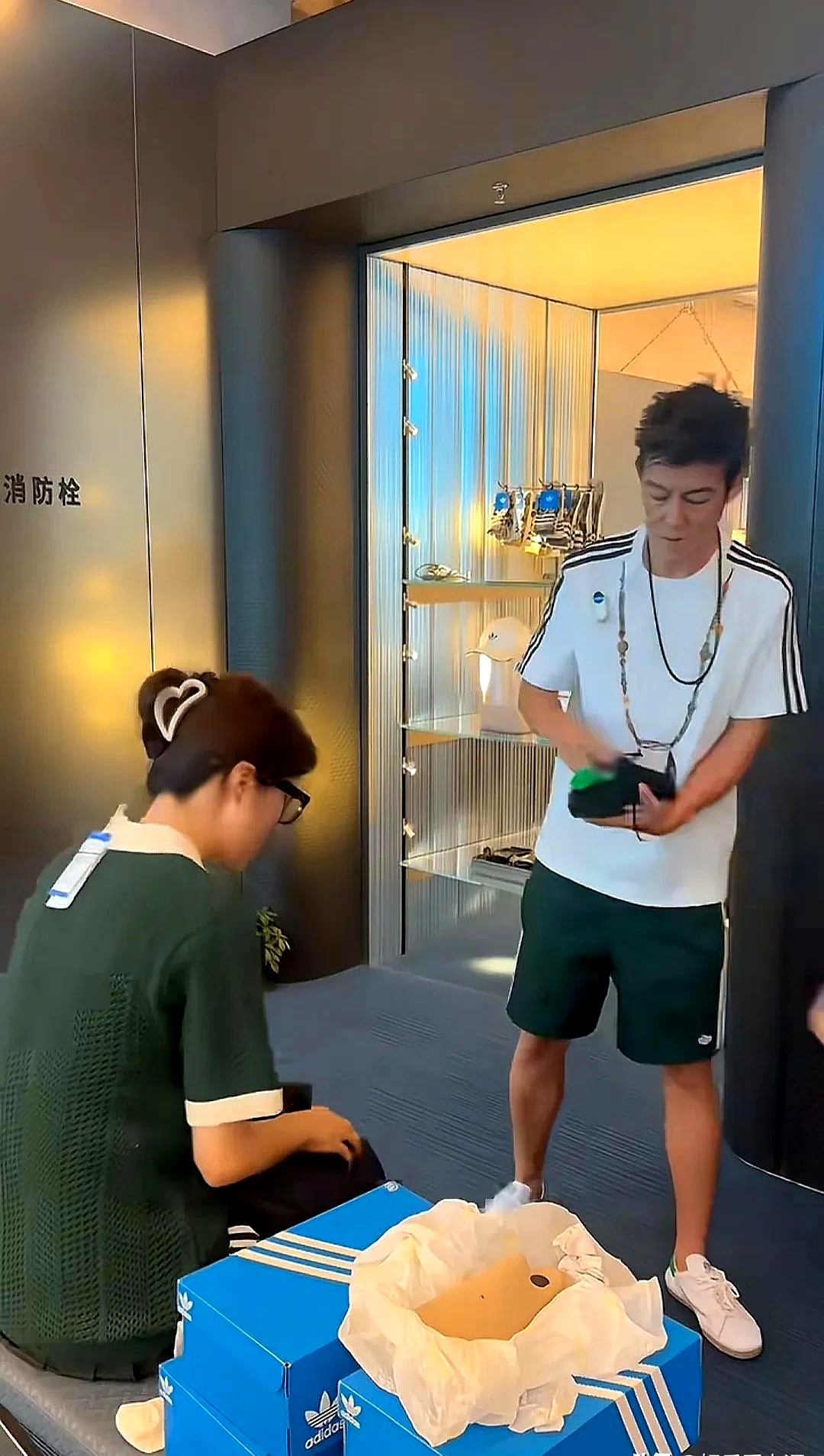 上海阿迪达斯旗舰店的监控画面里一个穿黑色工装裤的男人正单膝跪地