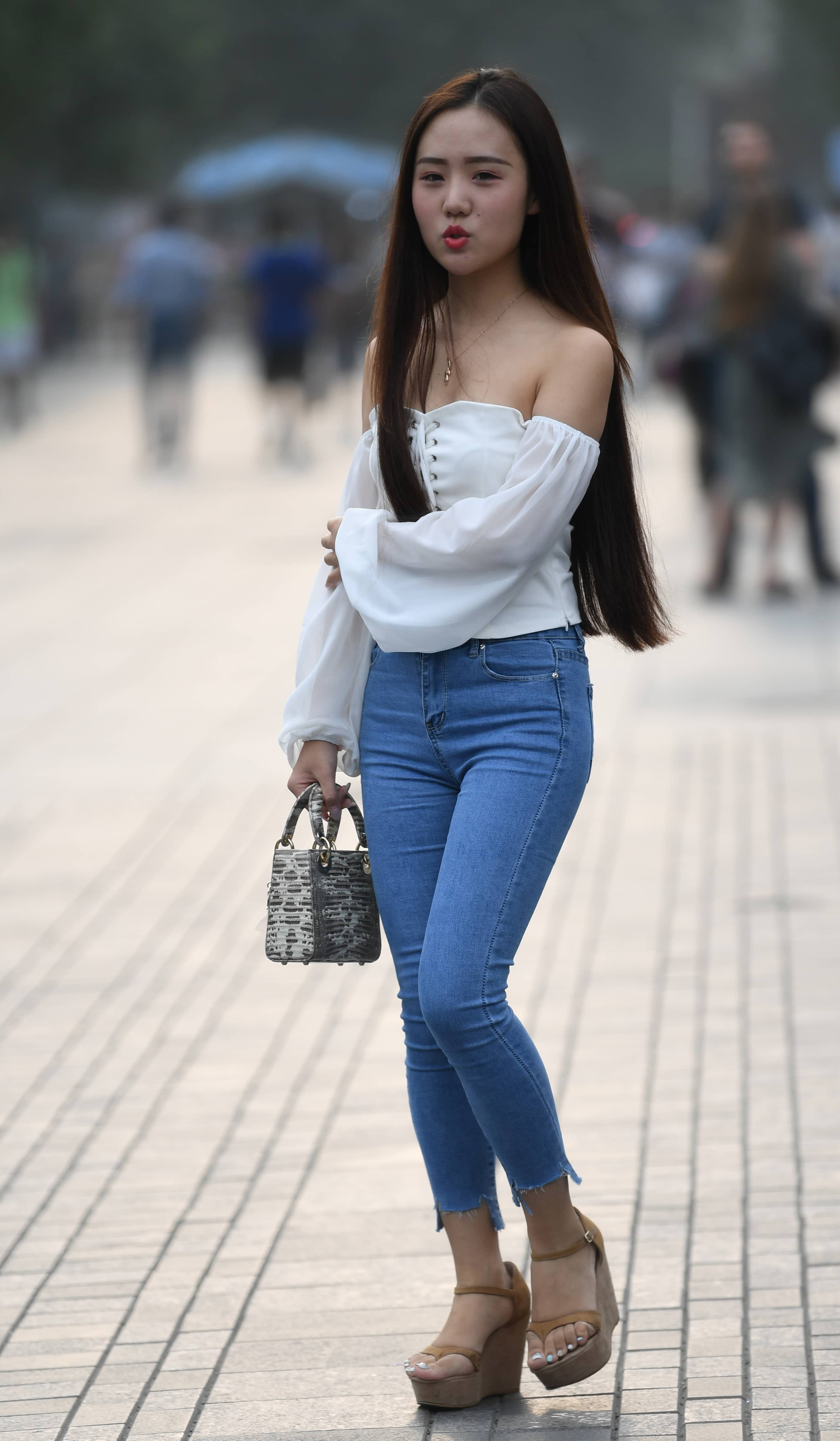 白色露肩灯笼袖上衣清新吸睛,搭浅蓝紧身牛仔裤,棕色厚底坡跟鞋,手提