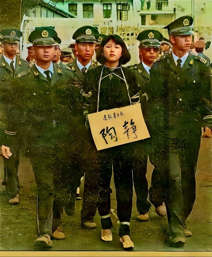 女子身穿一身黑色西服套装,脖子上挂着一个牌子,踝