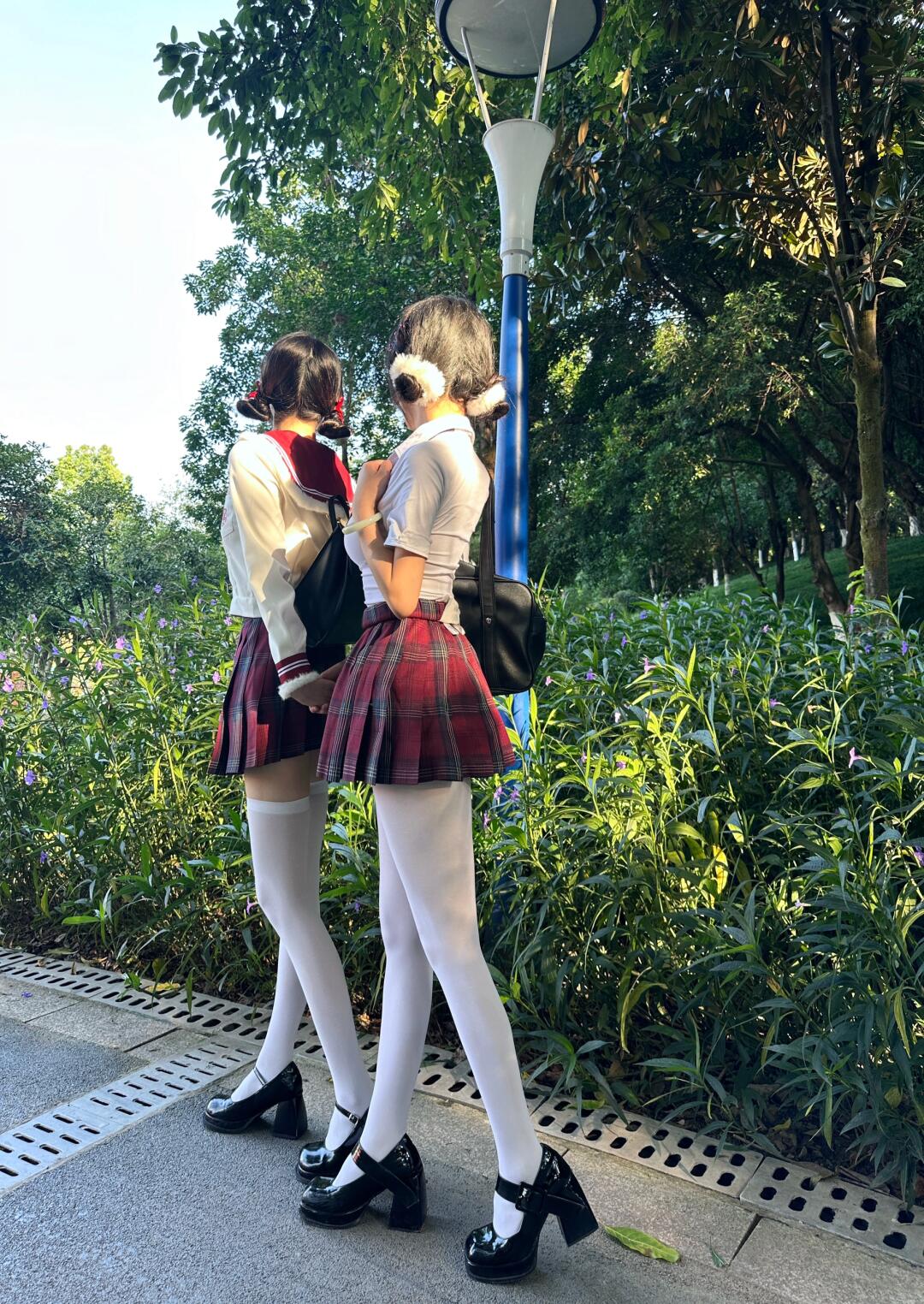 两位小姐姐穿着jk制服在公园里散步阳光洒在她们身上显得格外青春