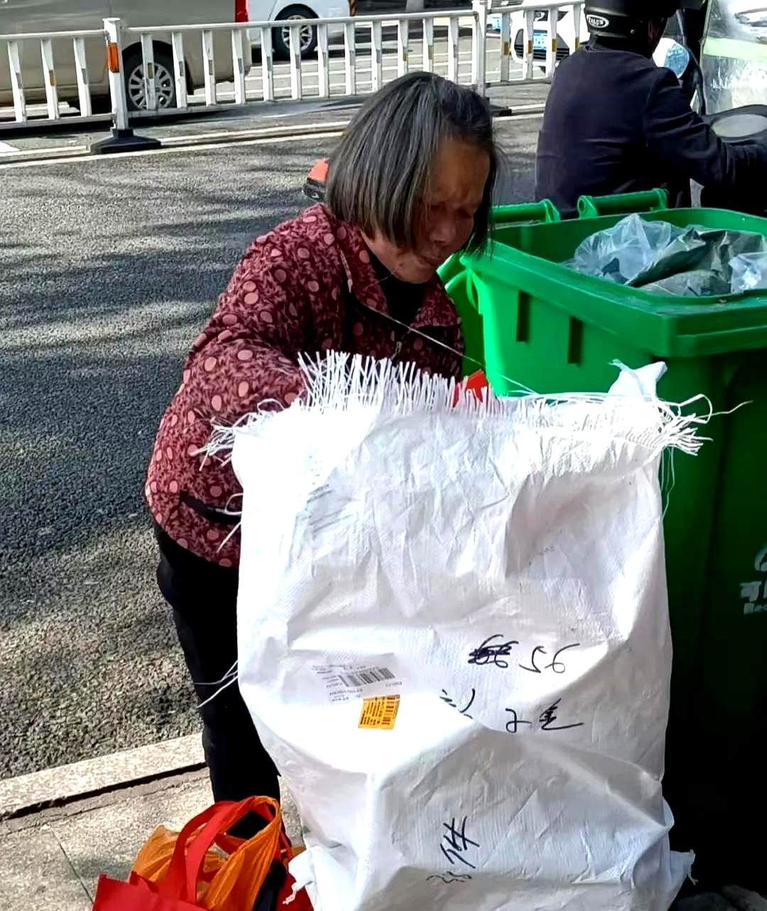 她踮着脚尖在捡拾塑料瓶灰布衫后背都被汗水浸湿了