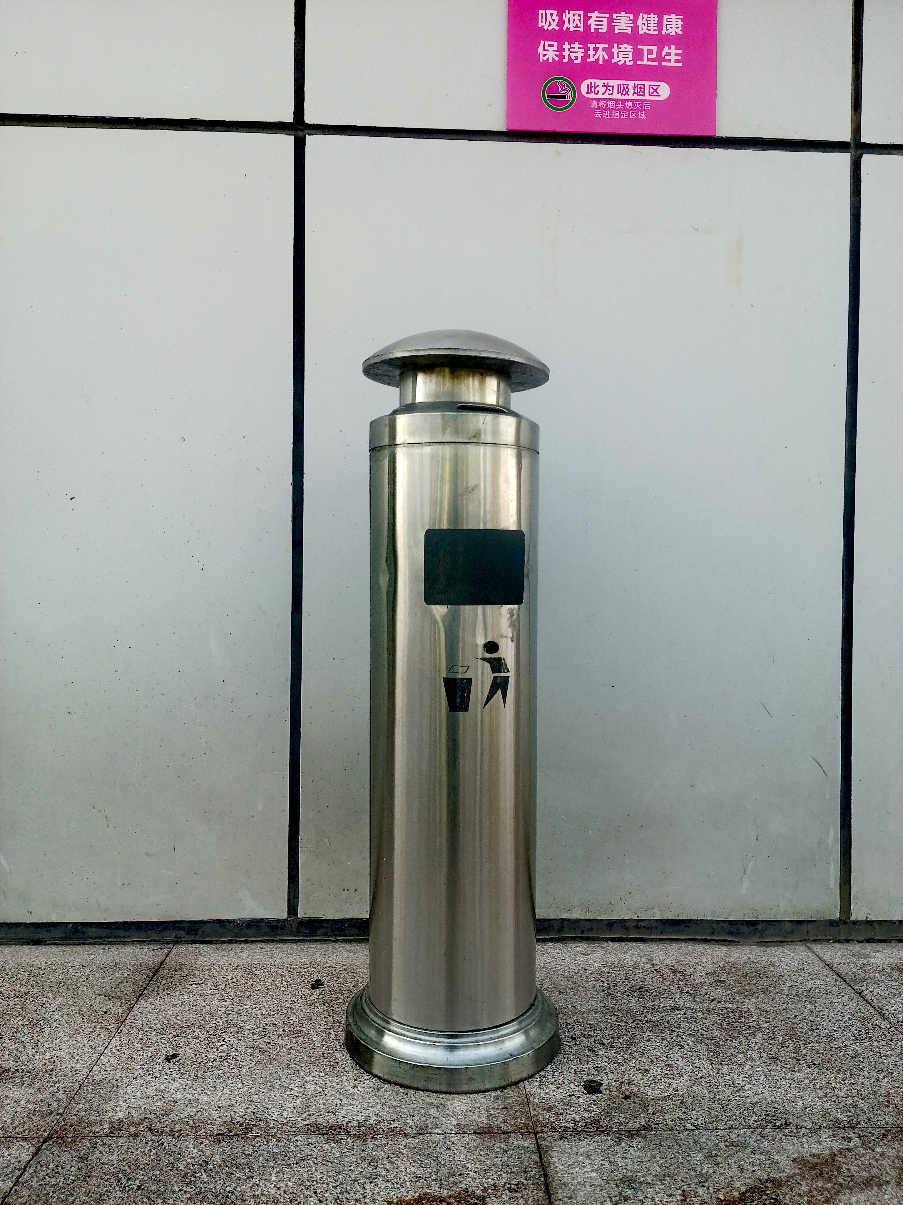 此为吸烟区,"旁边立着个不锈钢烟灰桶,提醒着大家注意吸烟礼仪