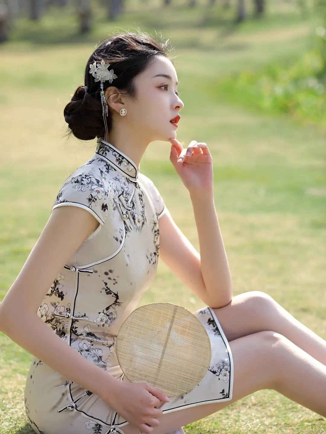 在温柔的春光里,一位青春少女静坐于翠绿的草地,身着洁白旗袍,轻盈如