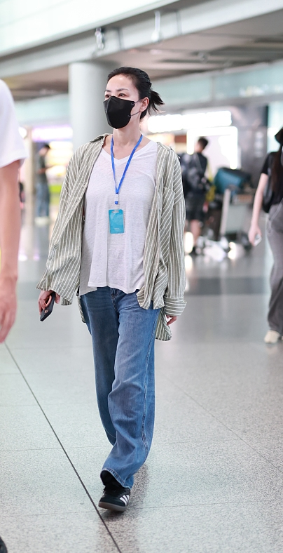 动态夏日征集令# 王菲机场街拍,她穿了一件米色的条纹衬衫,内搭白t恤