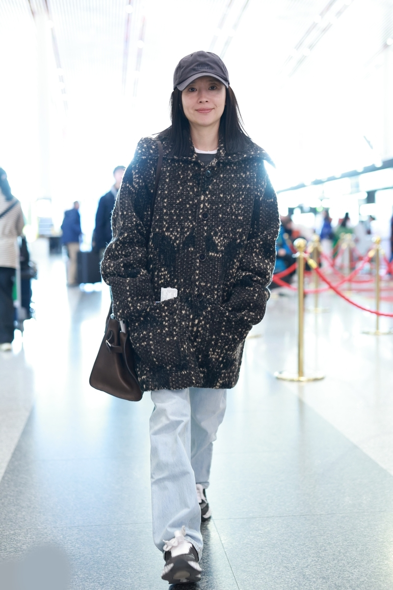 董洁机场街拍来了,她戴了一顶深灰色的棒球帽,穿一件黑色夹花的翻领中