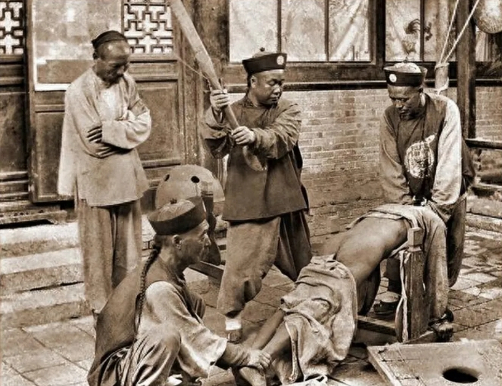 晚清时期,一位犯人正在被行刑时的瞬间,照片中一位官兵手持杀威棍