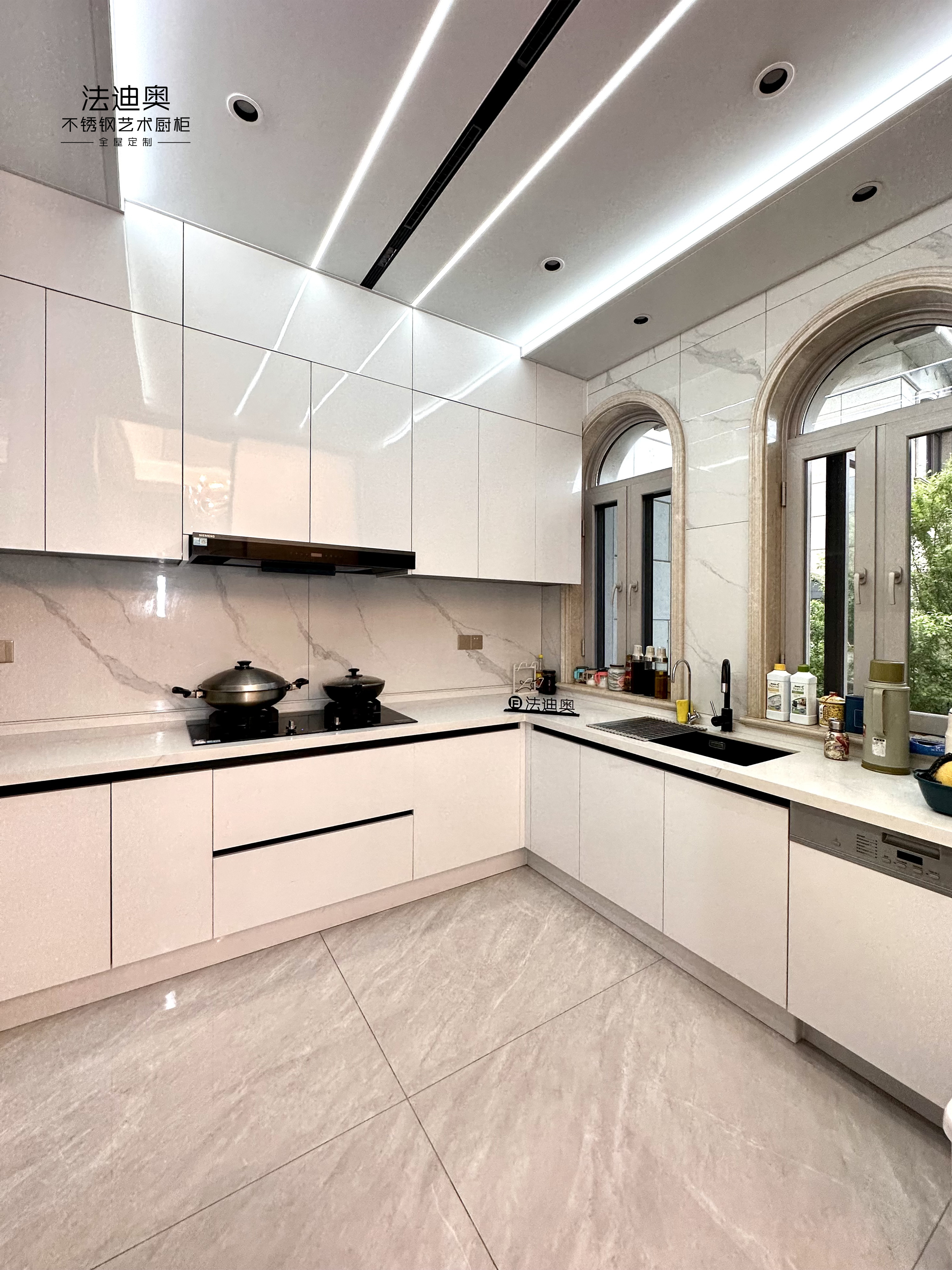 镜面不锈钢橱柜门板 在柔和的灯光下熠熠生辉, 而隐藏式的拉手设计则