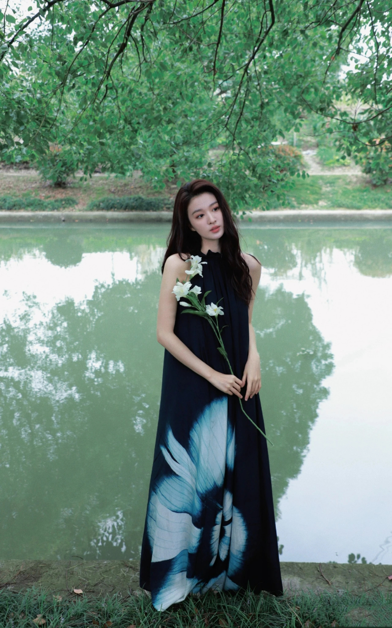 王楚然身着长款无袖露肩褶皱印花连衣裙, 站立在湖畔,清冷大气.