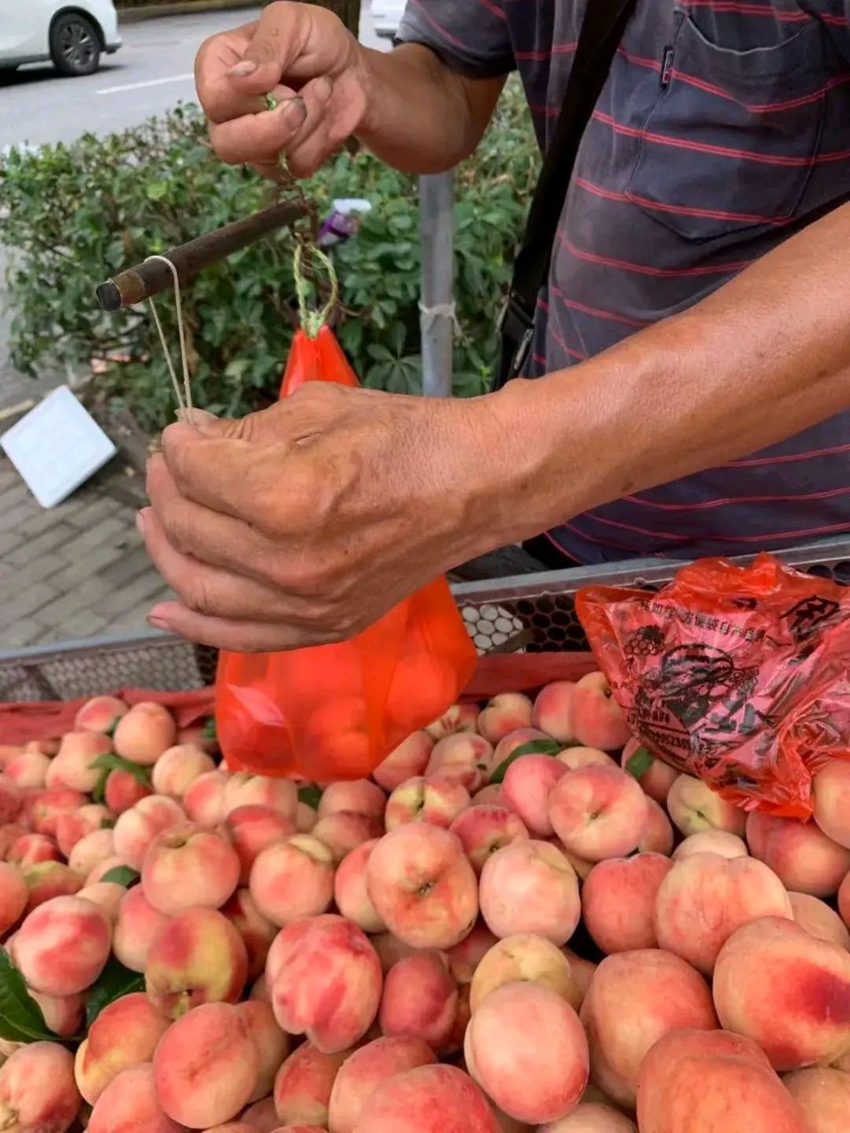 一大爷推着板车在路边卖桃子,遭旁边卖菜大妈抱怨,微信收款还有把收款