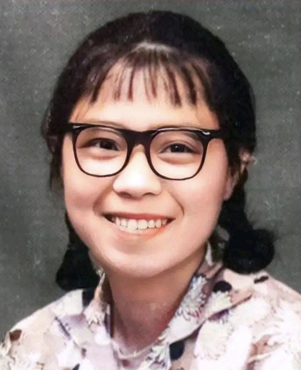 1974年,张桂梅老师年轻时的照片,镜头中的她戴着黑框眼镜,笑容灿烂,有