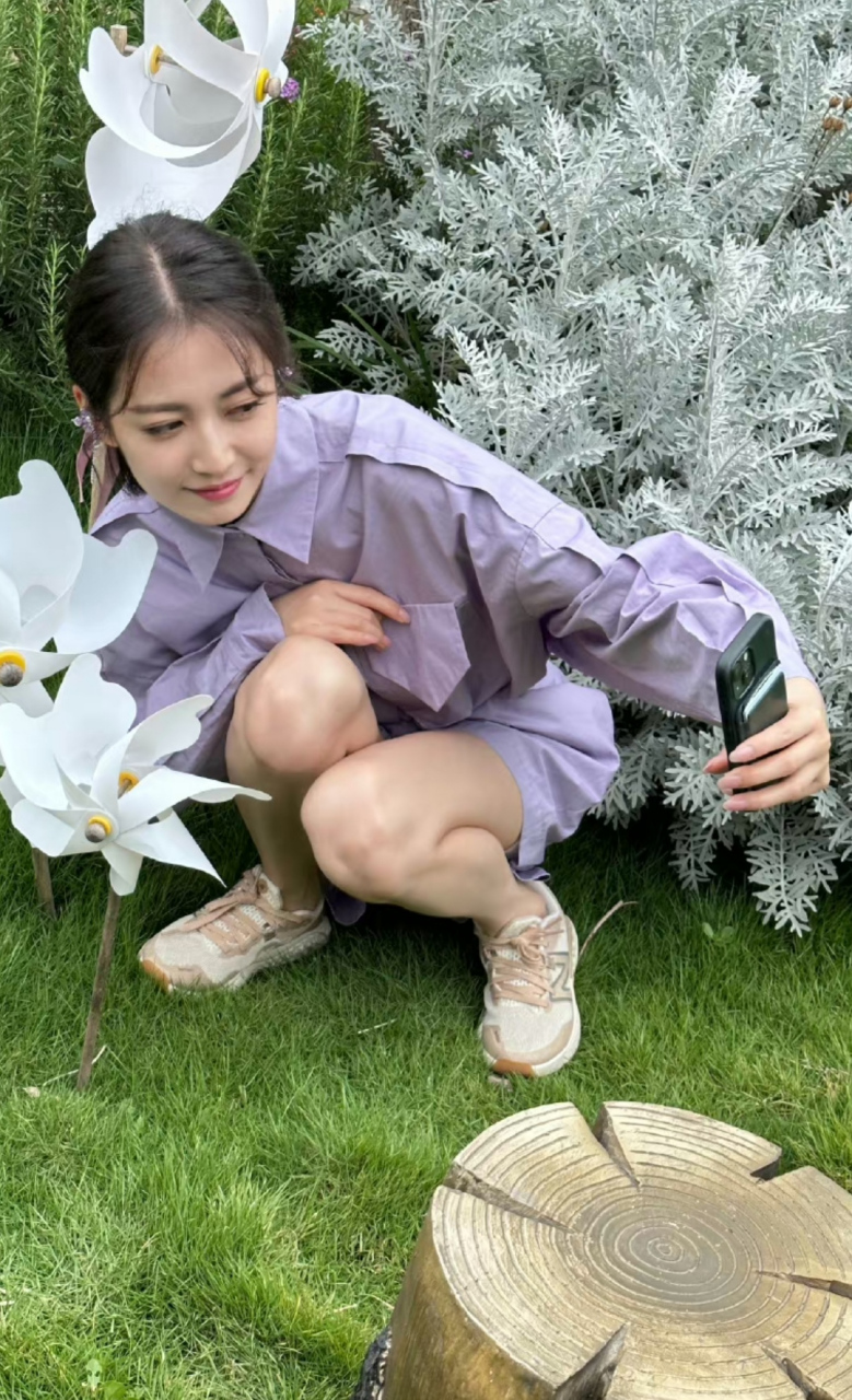 陈钰琪蹲在草坪上自拍,还特意找角度把白色风车拍进去,取景很专业.