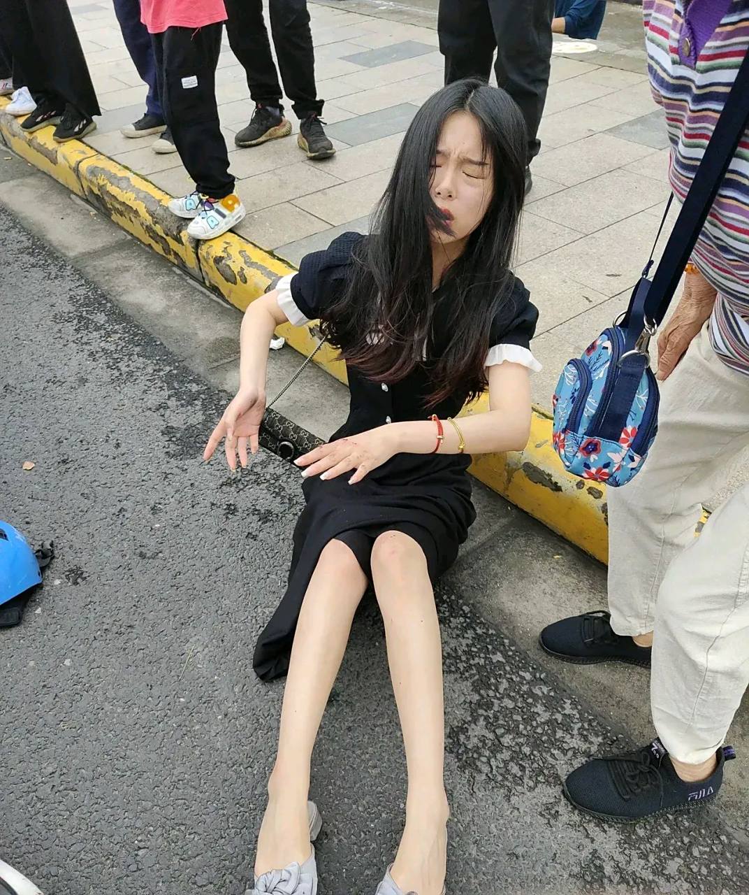 两位女子开着电动车相撞在一起,两人都摔倒在地,小姑娘趴在地上面目