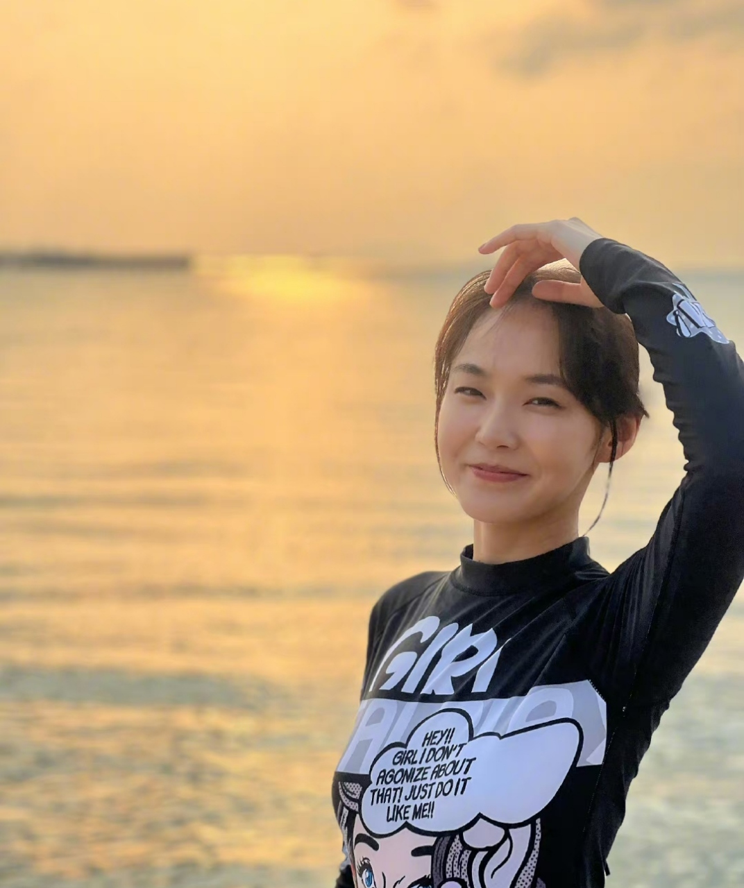 张佳宁戴着粉色帽子减龄十足,身后阳光照着大海,画面岁月静好.