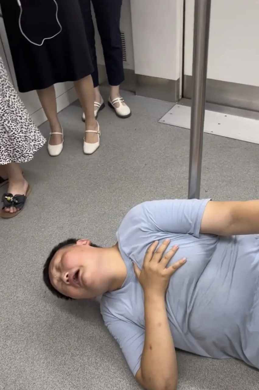 重庆,地铁车厢中,一名男孩长相的人突然倒地不起,用手捂着自己的胸口