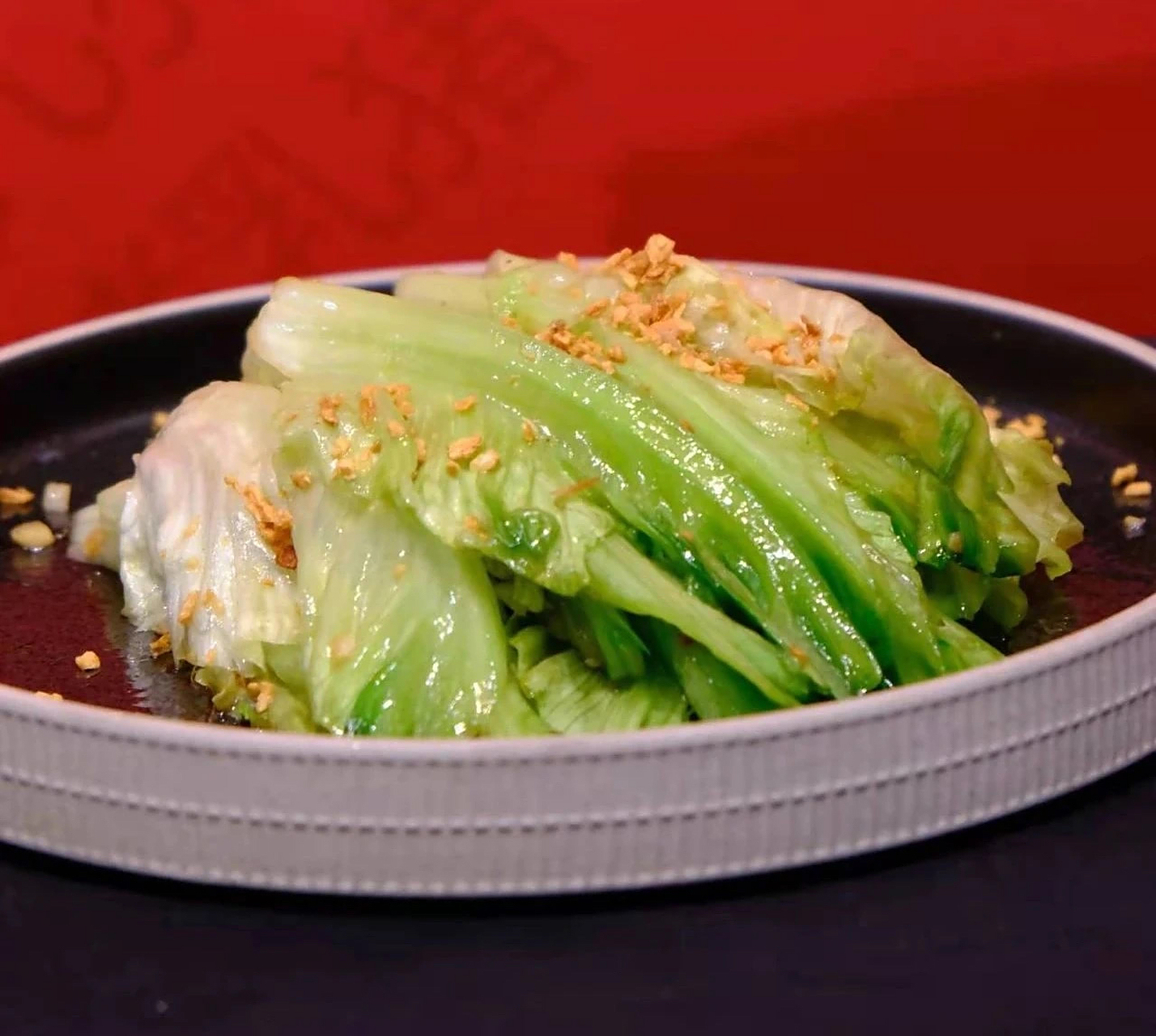 热锅冷油,下入蒜蓉,爆炒出香,下入生菜梗,调入适量盐,糖,大火翻炒至青