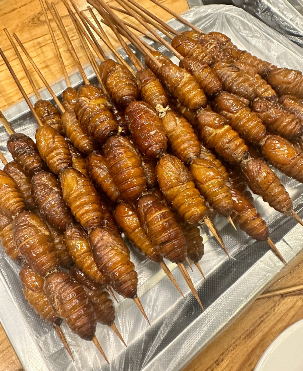 林峯老婆真敢吃,一家人去北京旅游点了30串烤蚕蛹,张馨月拿着烤串拍照